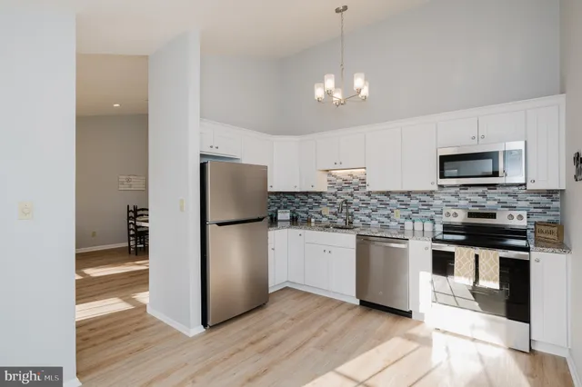 a kitchen with stainless steel appliances granite countertop a refrigerator a stove a microwave and white cabinets