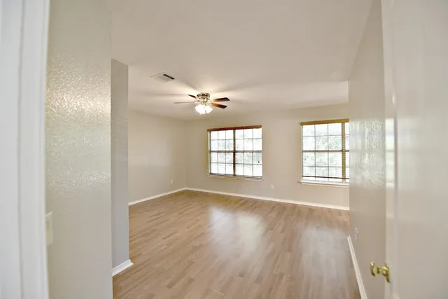 a view of an empty room with wooden floor and a window