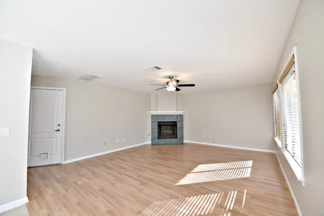a view of a livingroom with a fireplace a ceiling fan and windows