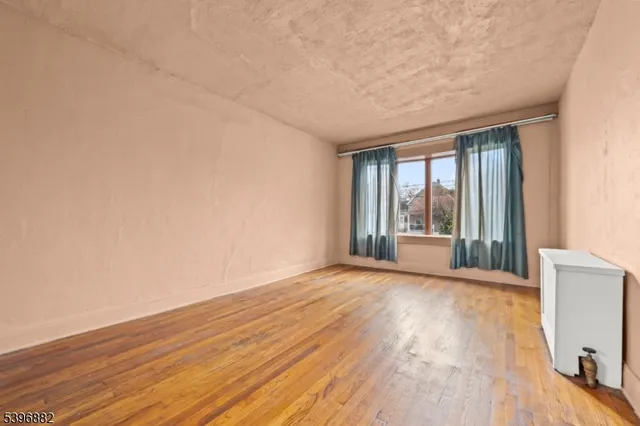 a view of an empty room with glass door and wooden floor