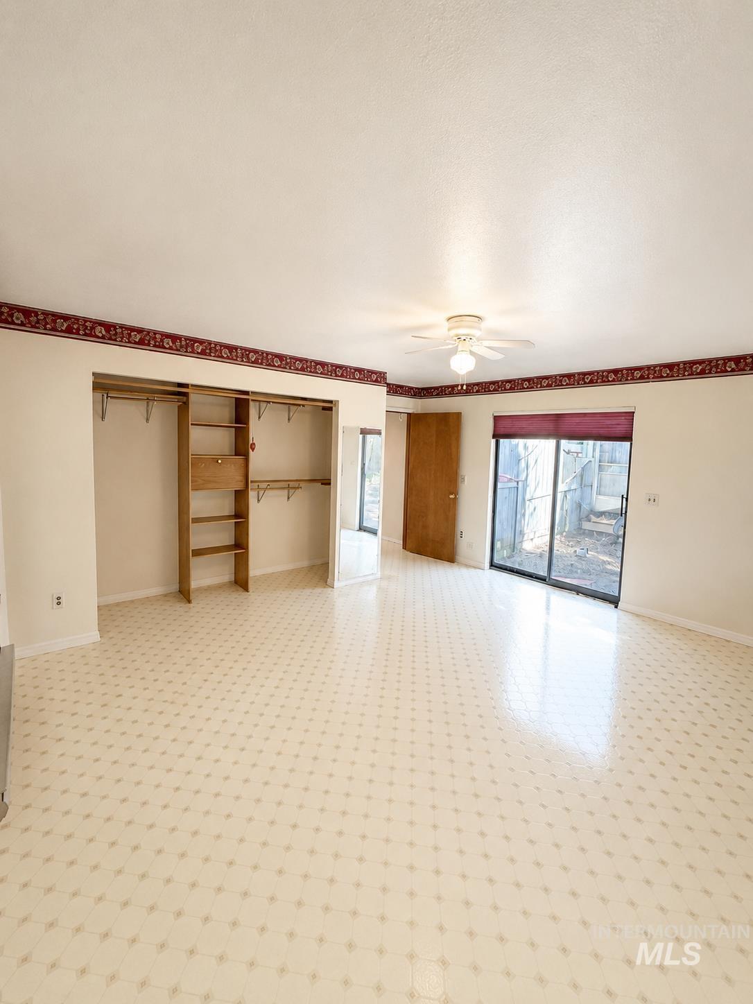 16434 Pride Lane Caldwell, ID 83607 - Photo 11 of 16 Spacious room featuring patterned tile flooring, an open closet with built-in shelving and hanging rods, a ceiling fan with integrated lighting, and a sliding glass door providing exterior access