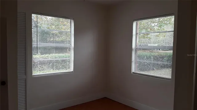 a view of empty room with wooden floor and windows