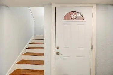 a view of a hallway with stairs and a white door