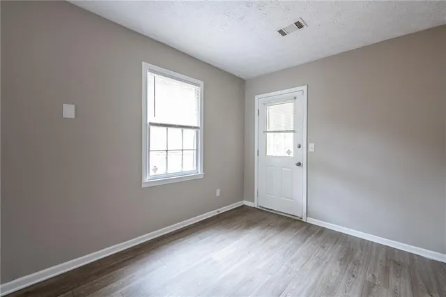 an empty room with wooden floor and windows