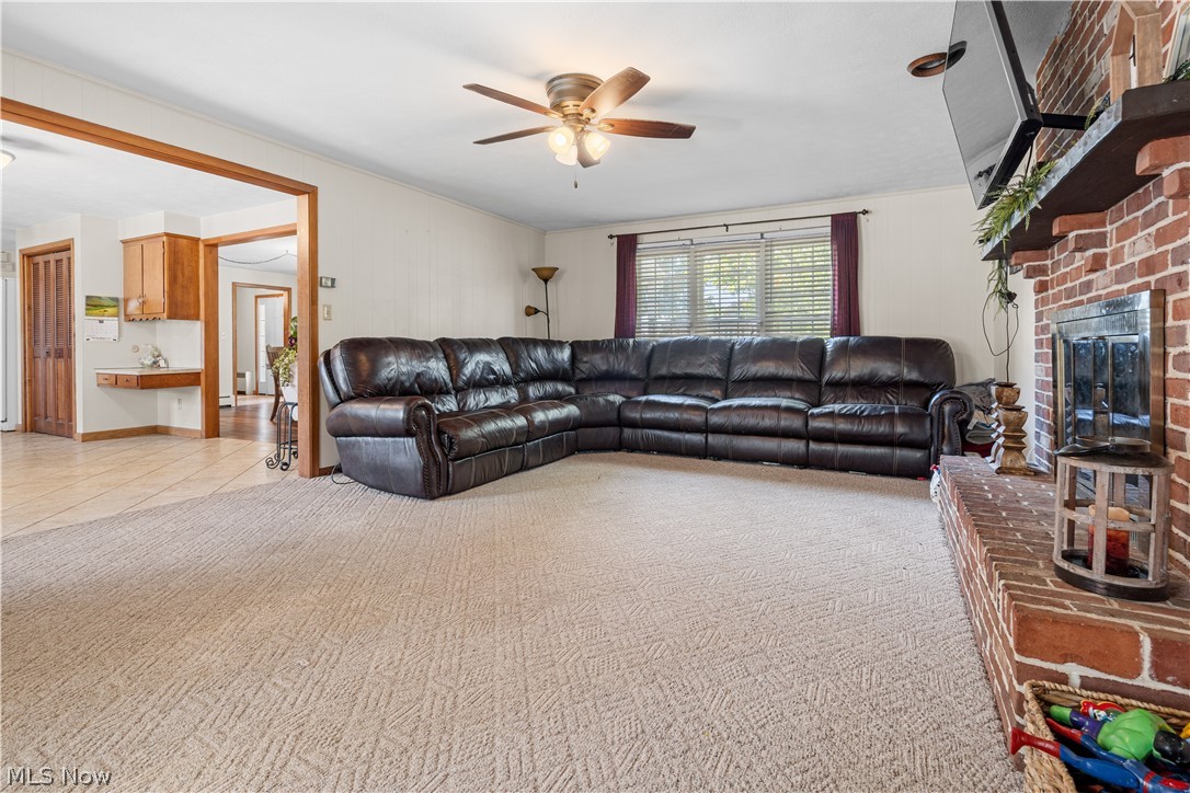 3650 Rambo Avenue Alliance, OH 44601 - Photo 17 of 36 Carpeted living area with a brick fireplace, ceiling fan, and light wood trim