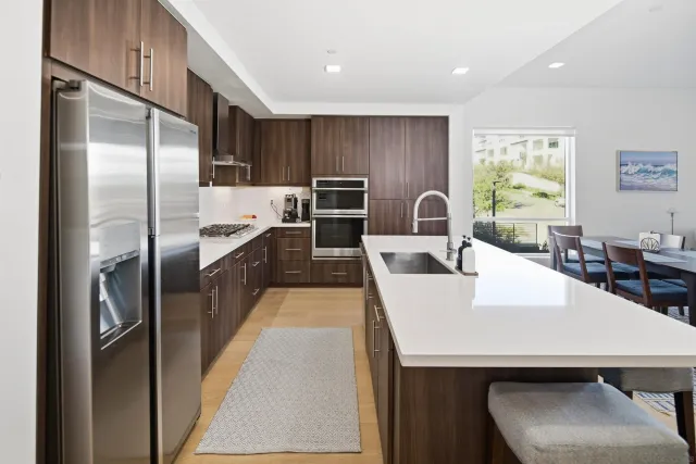 a large kitchen with kitchen island a counter top space a sink stainless steel appliances and cabinets