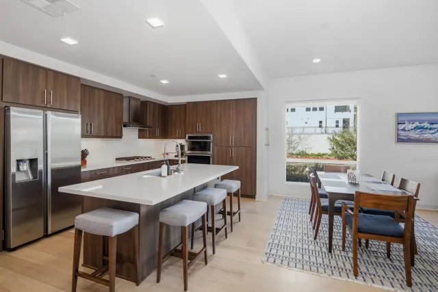 a kitchen with stainless steel appliances granite countertop a stove a refrigerator a kitchen island a table and chairs
