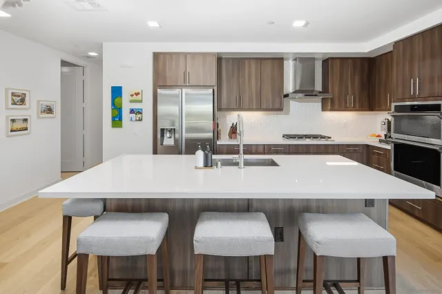 a kitchen with stainless steel appliances a table chairs in it and wooden floors