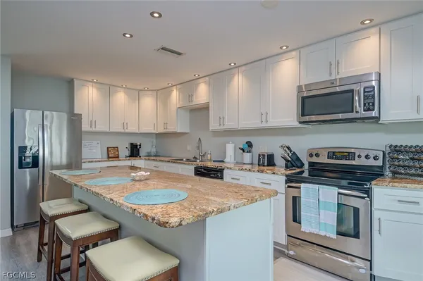 a kitchen with granite countertop a stove top oven a sink dishwasher a refrigerator and cabinets with wooden floor