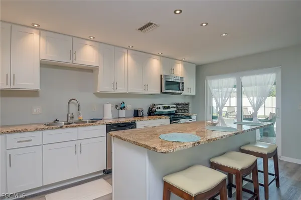 a kitchen with sink a stove and chairs