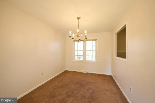 an empty room with chandelier fan and windows