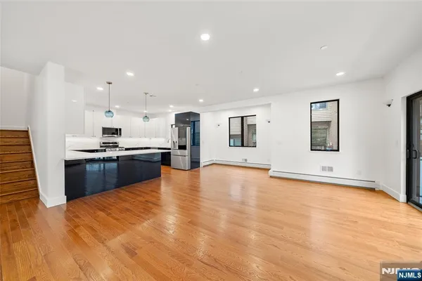 a living room with stainless steel appliances kitchen island granite countertop a large kitchen island a sink a stove and a wooden floors