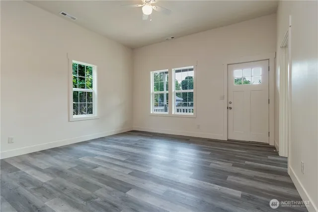 an empty room with wooden floor chandelier fan and windows