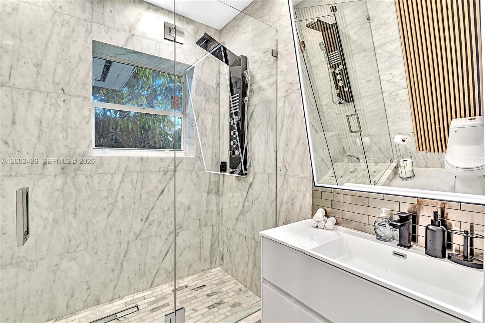 1002 10th Street, Unit 1002 Miami Beach, FL 33139 - Photo 51 of 71 a bathroom with a sink and mirror with bathtub