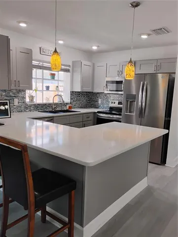 a kitchen with stainless steel appliances a dining table chairs refrigerator and microwave