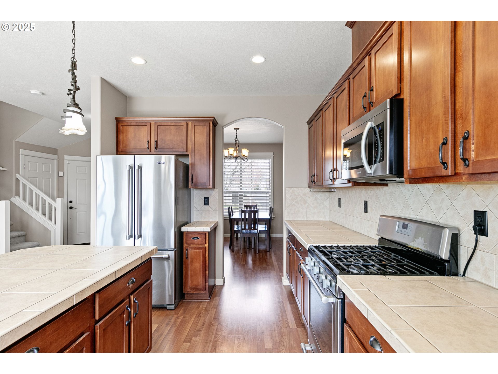 5462 Pranz Place Eugene, OR 97402 - Photo 18 of 43 a kitchen with stainless steel appliances granite countertop a refrigerator oven stove a sink a dining table and chairs with wooden floor