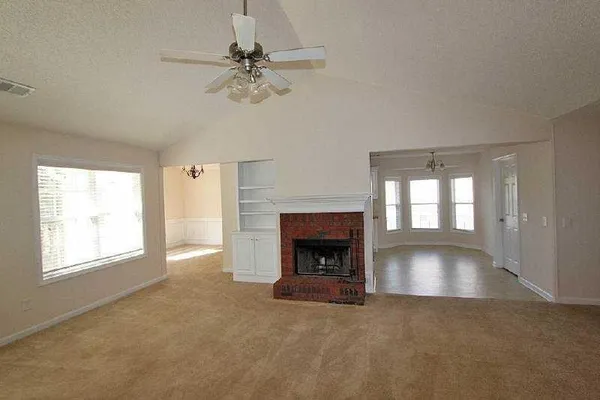 an empty room with windows and fireplace