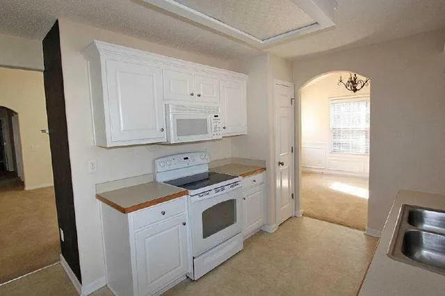 a kitchen with granite countertop white cabinets and white appliances