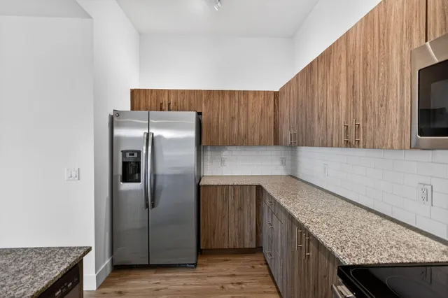 a kitchen with stainless steel appliances granite countertop a refrigerator a oven and wooden cabinets