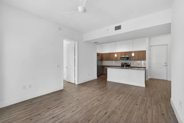 a view of kitchen with stainless steel appliances wooden floor and chair
