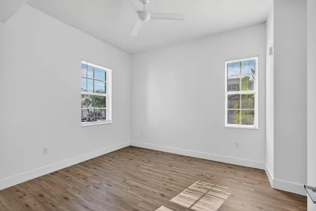 an empty room with wooden floor and windows