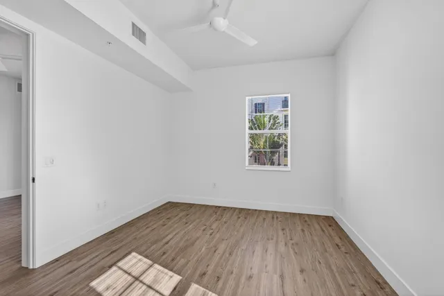 an empty room with wooden floor and windows