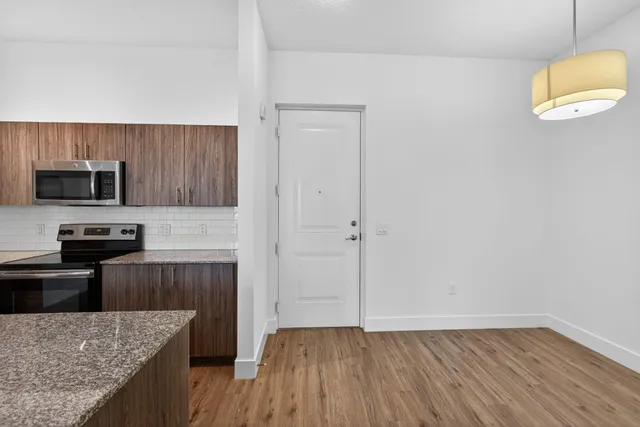 a kitchen with granite countertop a microwave a stove and a wooden floors