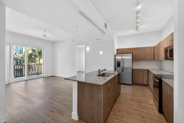 a kitchen with stainless steel appliances granite countertop a refrigerator a sink dishwasher a stove and a oven with wooden floor