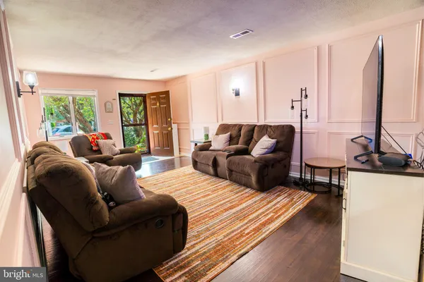 a living room with furniture flat screen tv and a large window
