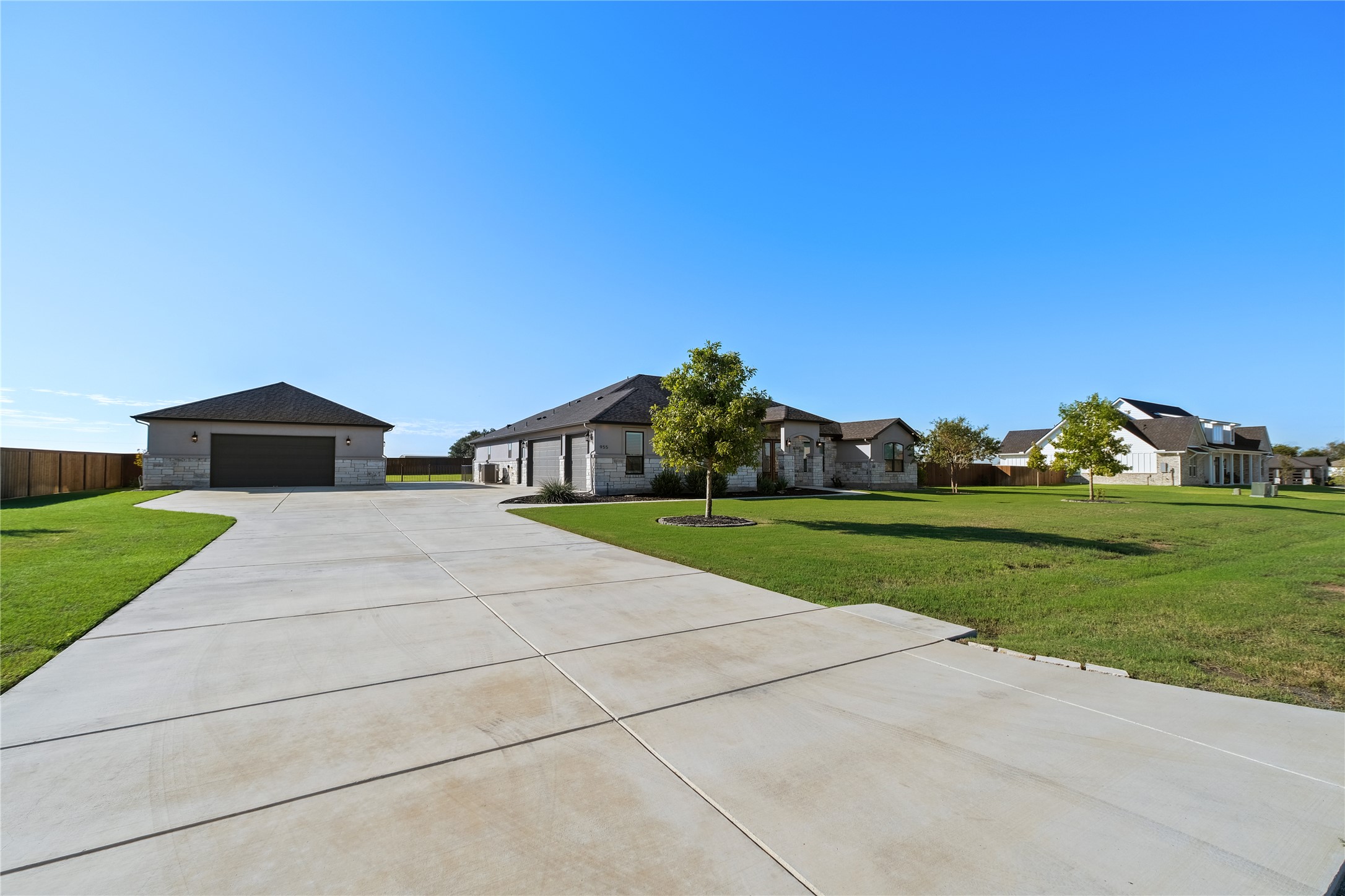 955 Inka Road Salado, TX 76571 - Photo 35 of 39 An expansive concrete driveway leads past the detached garage toward a stately stone-accented home.