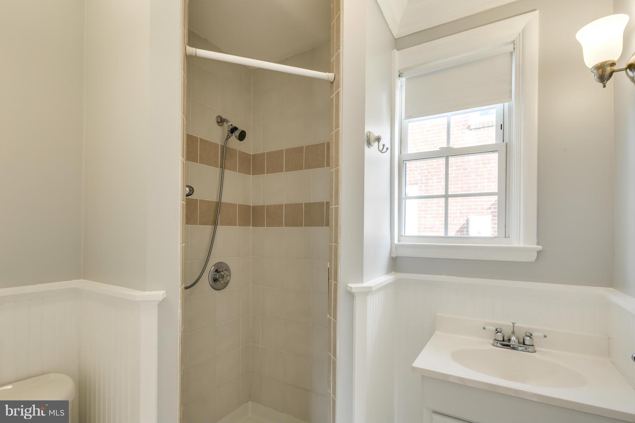 6704 Campfield Road Baltimore, MD 21207 - Photo 16 of 30 a bathroom with a sink a window and shower