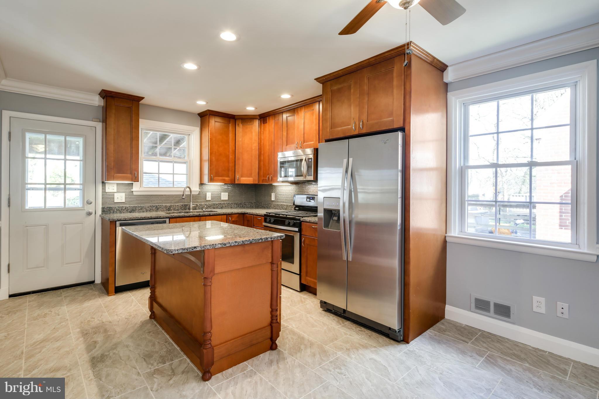6704 Campfield Road Baltimore, MD 21207 - Photo 4 of 30 a kitchen with stainless steel appliances granite countertop a refrigerator a sink a stove and wooden cabinets