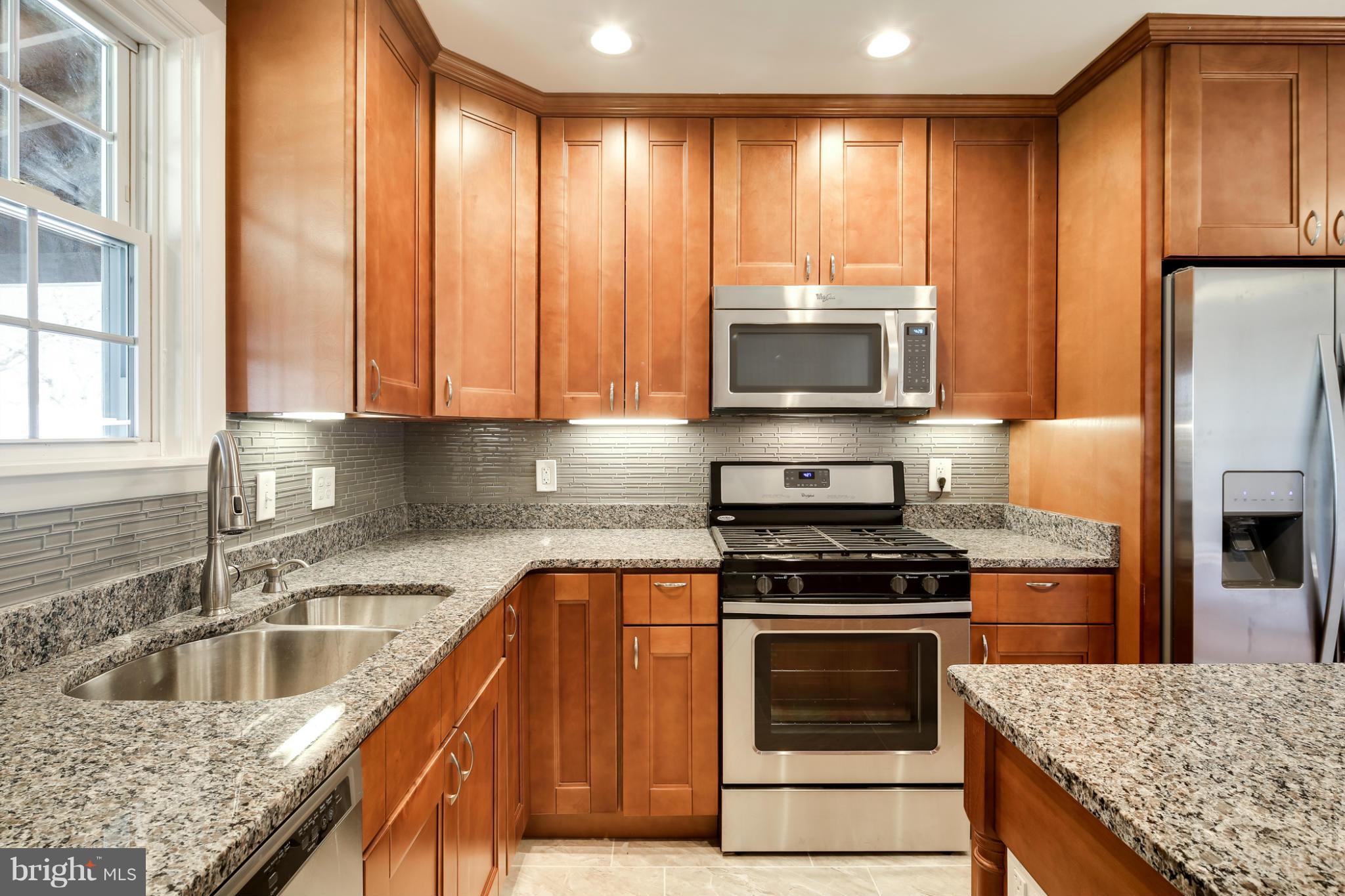 6704 Campfield Road Baltimore, MD 21207 - Photo 5 of 30 a kitchen with granite countertop a stove a sink and a refrigerator