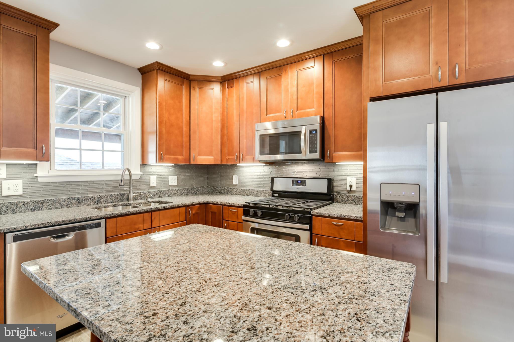 6704 Campfield Road Baltimore, MD 21207 - Photo 6 of 30 a kitchen with stainless steel appliances granite countertop a stove a sink and a refrigerator