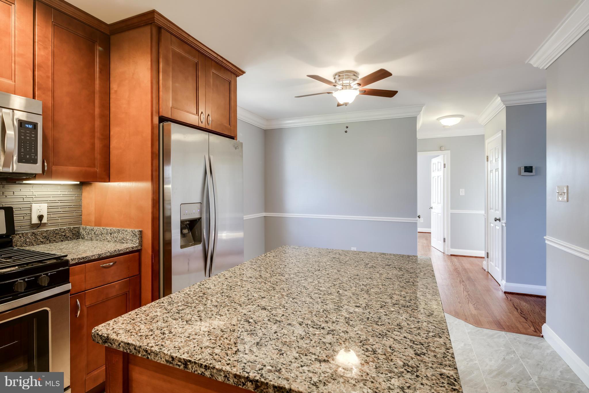 6704 Campfield Road Baltimore, MD 21207 - Photo 7 of 30 a kitchen with stainless steel appliances granite countertop a refrigerator and a stove top oven