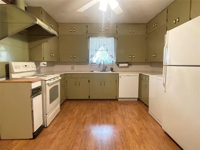 a kitchen with a sink a refrigerator and wooden floor