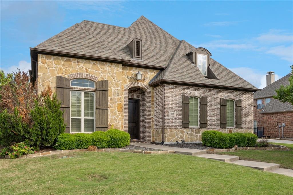 580 Butchart Drive Prosper, TX 75078 - Photo 38 of 40 French country inspired facade with stone siding, a front yard, brick siding, and roof with shingles
