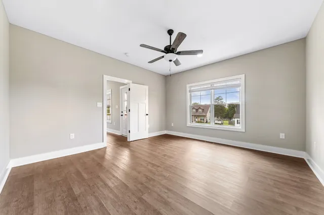 an empty room with wooden floor chandelier and windows