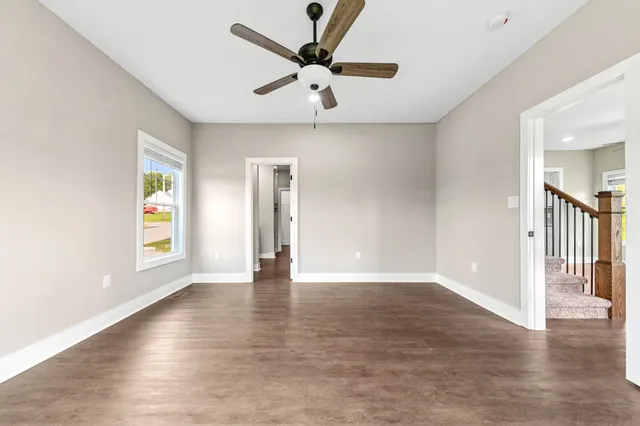 a view of an empty room with a window and wooden floor