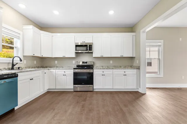 a kitchen with granite countertop white cabinets and stainless steel appliances