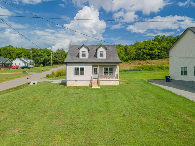 a view of a house with a big yard potted plants and large tree