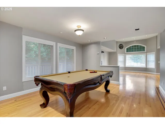 a room with furniture pool table wooden floor and windows
