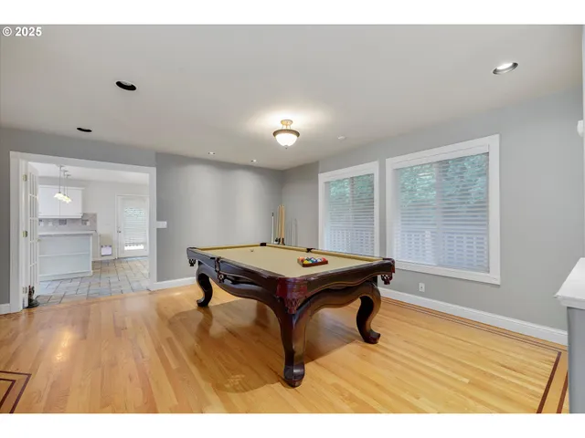 a room with furniture pool table wooden floor and windows