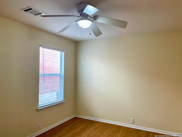 an empty room with a window and a fan