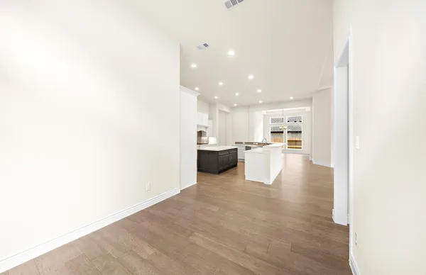 a view of an empty room with wooden floor and windows