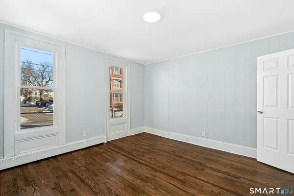 a view of an empty room with wooden floor and a window