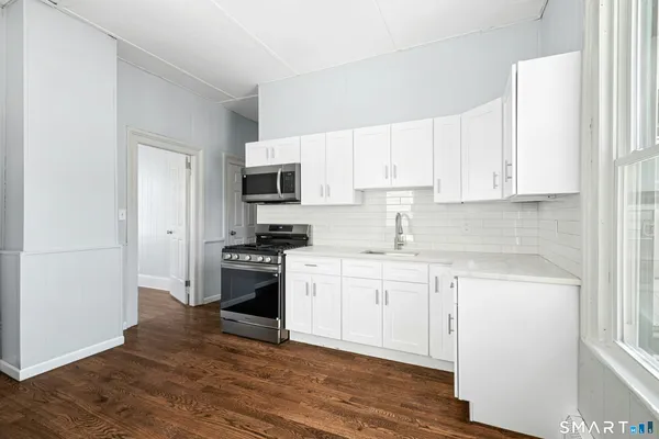 a kitchen with cabinets stainless steel appliances and wooden floor
