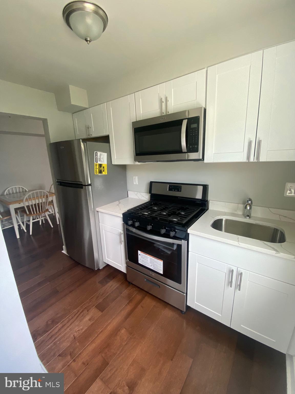 52 Forrester Street Southwest Washington, DC 20032 - Photo 15 of 18 a kitchen with stainless steel appliances granite countertop a stove a sink dishwasher a refrigerator a microwave oven with white cabinets and wooden floor