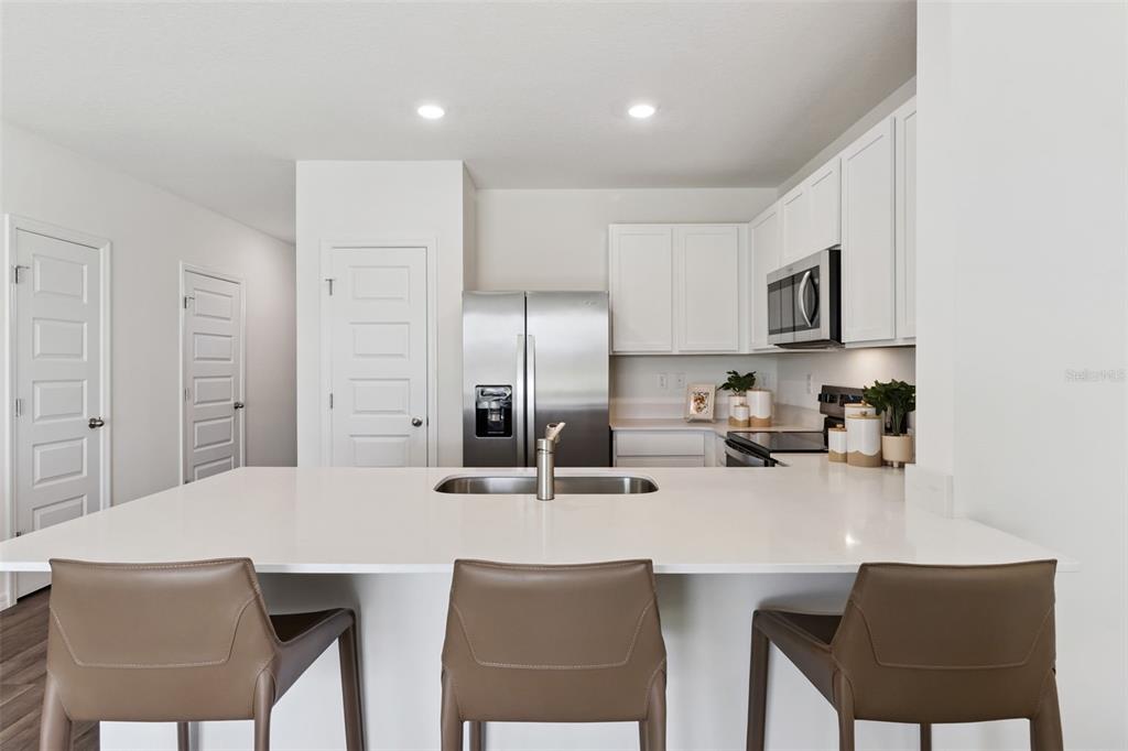 4356 Butterscotch Circle Lakeland, FL 33811 - Photo 8 of 30 a kitchen with stainless steel appliances a dining table chairs microwave and sink