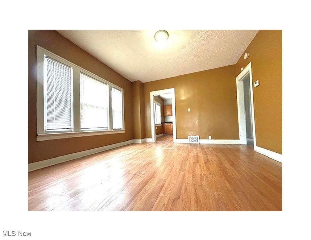 13436-13438 Hartford Road Cleveland, OH 44112 - Photo 3 of 5 Empty room with light wood-type flooring and a textured ceiling